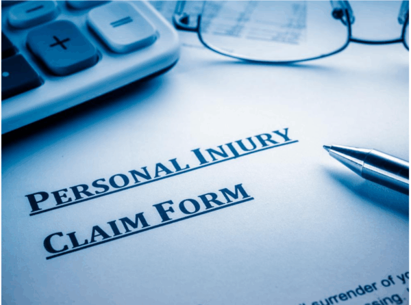 How_Long_Does_It_Take_to_Settle_an_Auto_Accident_Claim__docx_-_Google_Docs Personal injury claim form with a pen, glasses, and calculator in a blue-toned setting.