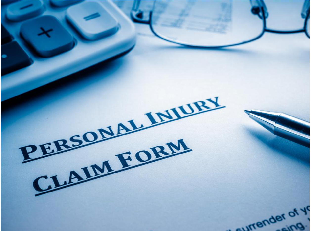 Personal injury claim form with a pen, glasses, and calculator in a blue-toned setting.