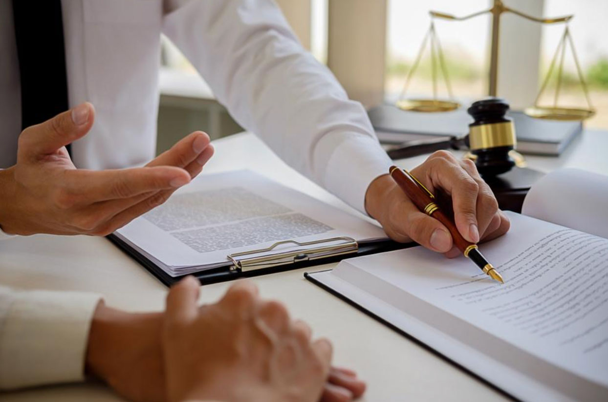Lawyer discussing contract with client, with legal documents and scales of justice in the background.