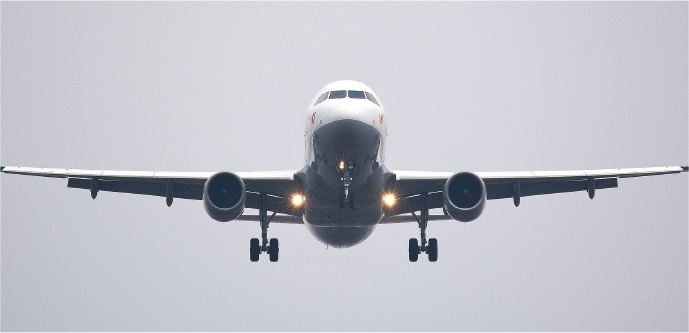 Airplane approaching landing with landing gear down on a cloudy day.