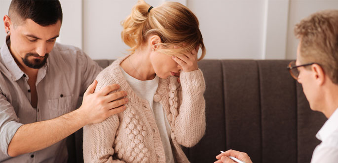 A supportive man comforts a distressed woman during a counseling session with a therapist.