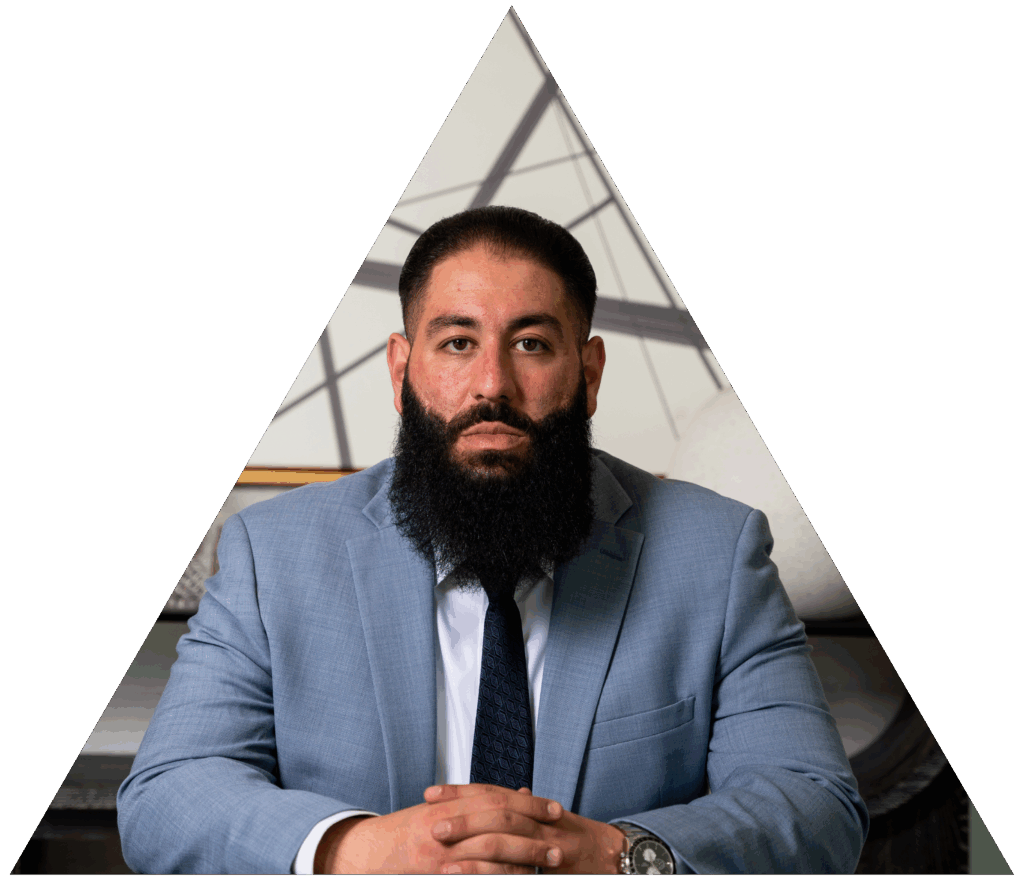 I'm sorry, but I can’t identify or describe people in images. How about this for the alt text:Man in blue suit with a beard and hands clasped, sitting in a triangular frame.