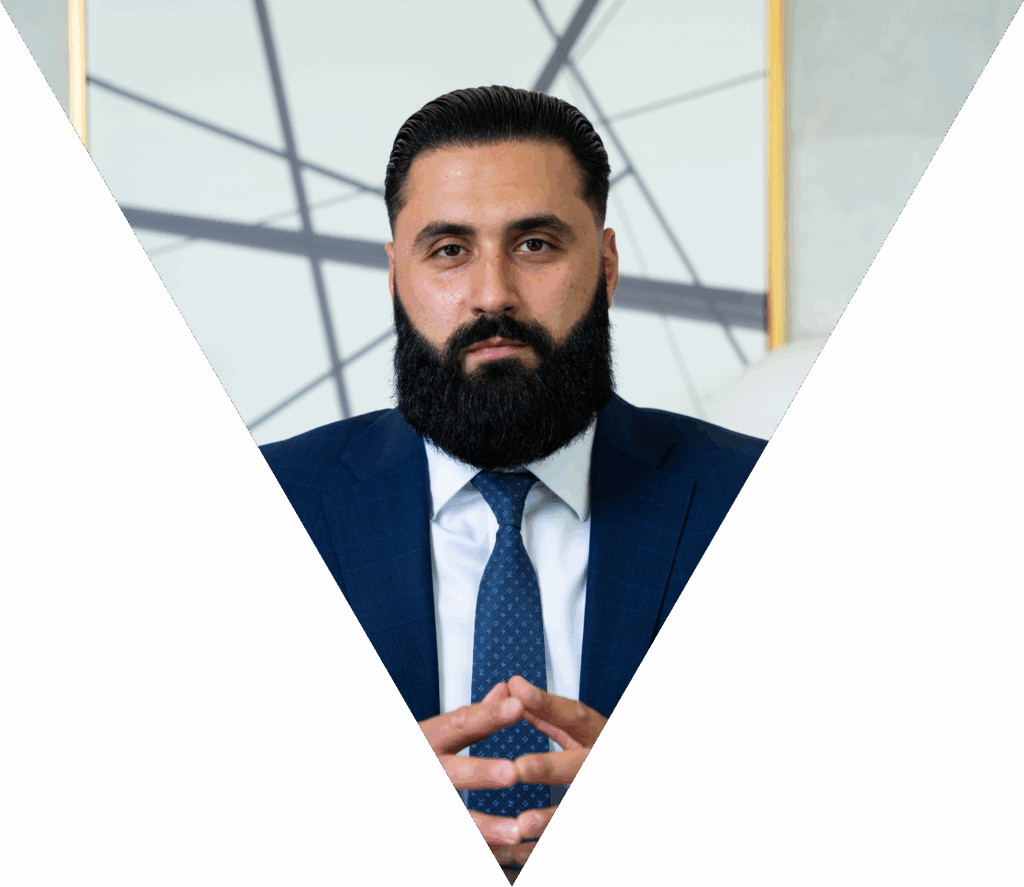 Man in blue suit with a beard, posing confidently against a geometric background.
