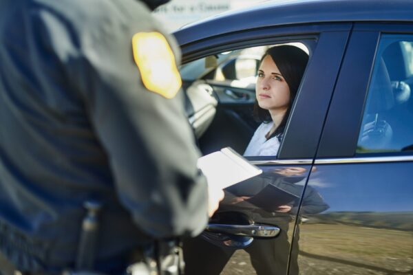 Writing,,Woman,And,Traffic,Officer,With,Ticket,For,Checkpoint,,Security law enforcement officer issuing ticket at car accident scene