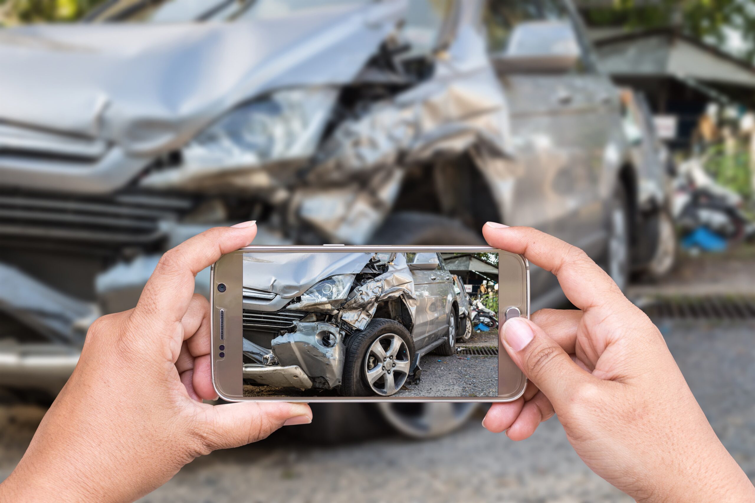 accident victim taking photos of car damage with smartphone after crash