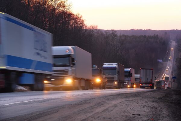 A semi-truck driving on a busy highway at sunset Commercial truck driving on highway representing causes of truck accidents.