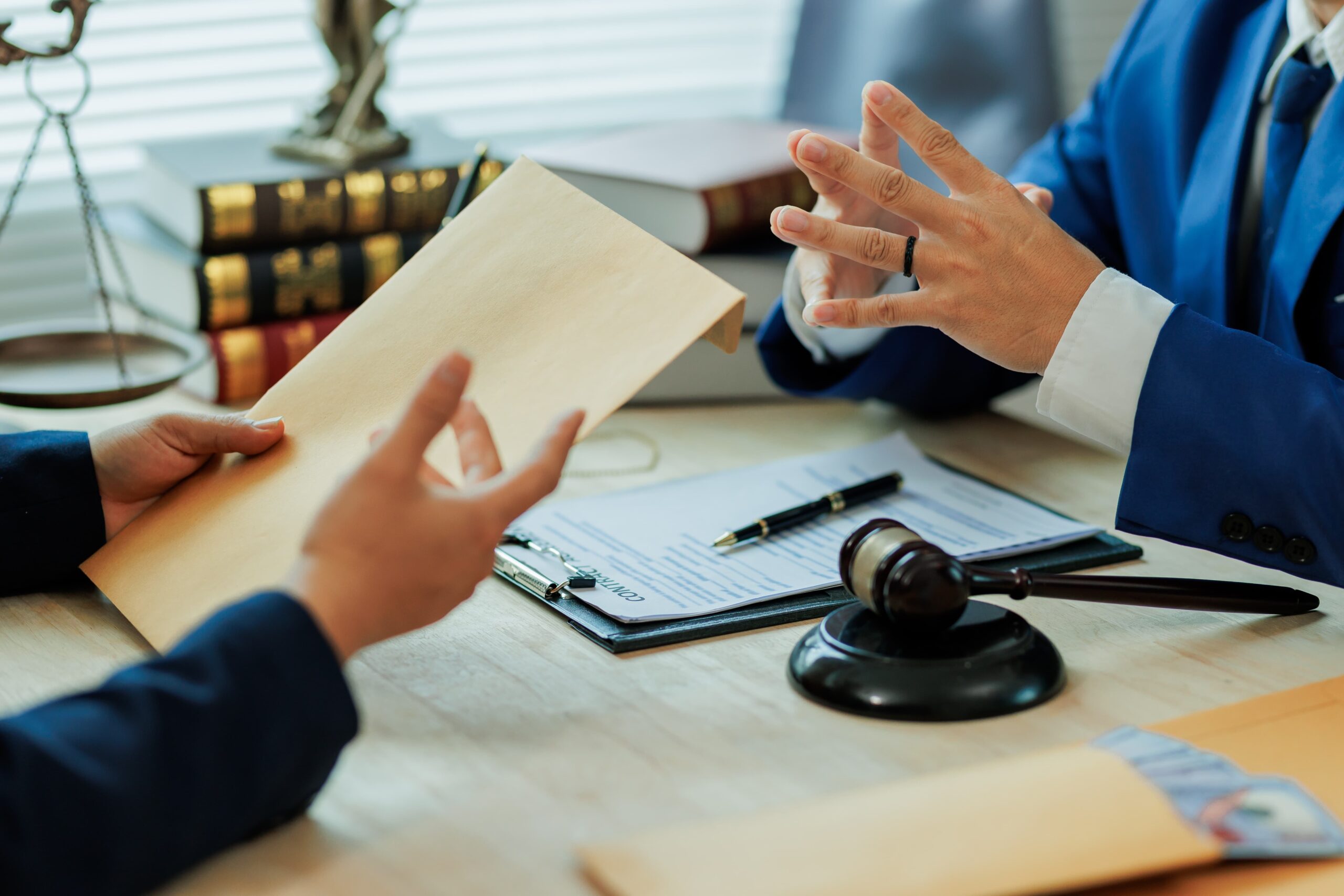 Two professionals in suits discussing legal documents with a gavel on the desk.