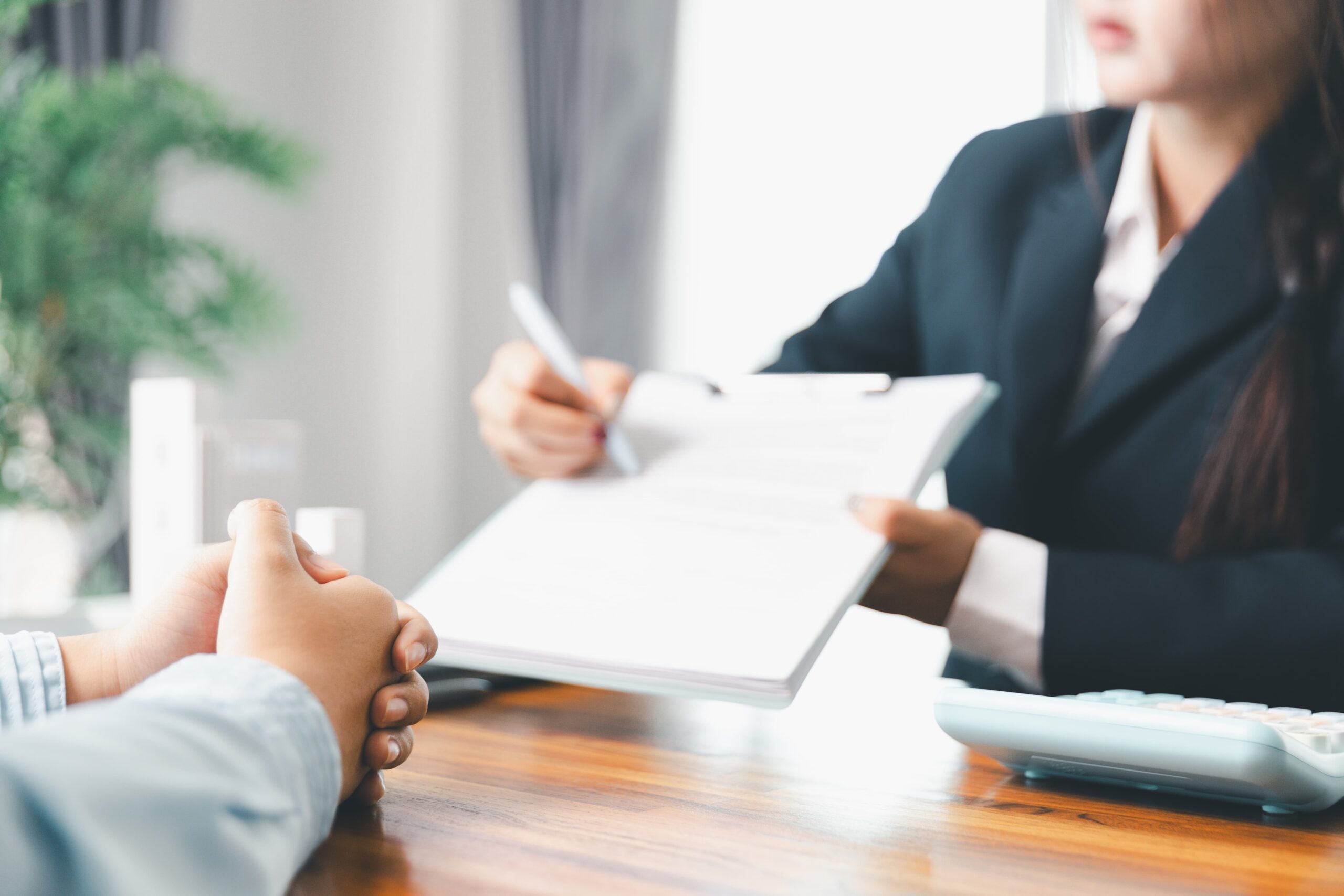 Business meeting with two professionals discussing documents at a wooden desk.