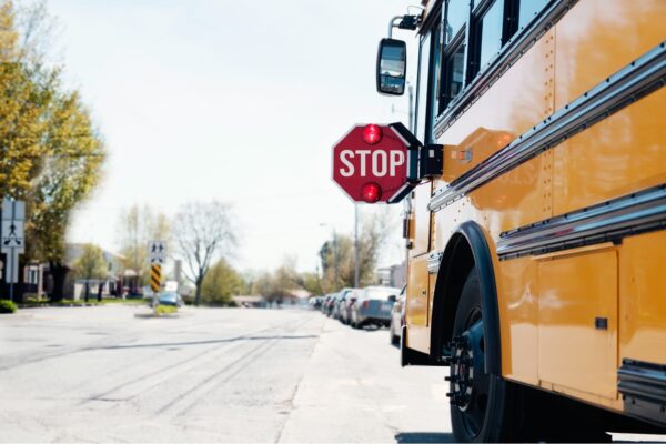 Yellow school bus stopped on the roadside with hazard lights on Filing a claim against a school bus operator after an accident