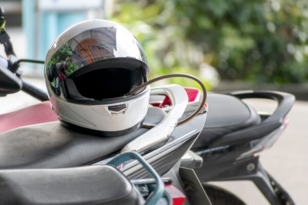 DOT-compliant full-face helmet on seat next to parked bike helmet laws motorcycle injury claim guide
