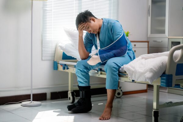 How to File a Catastrophic Injury injured person sitting on a hospital bed after a serious car crash, thinking about how to file a catastrophic injury claim