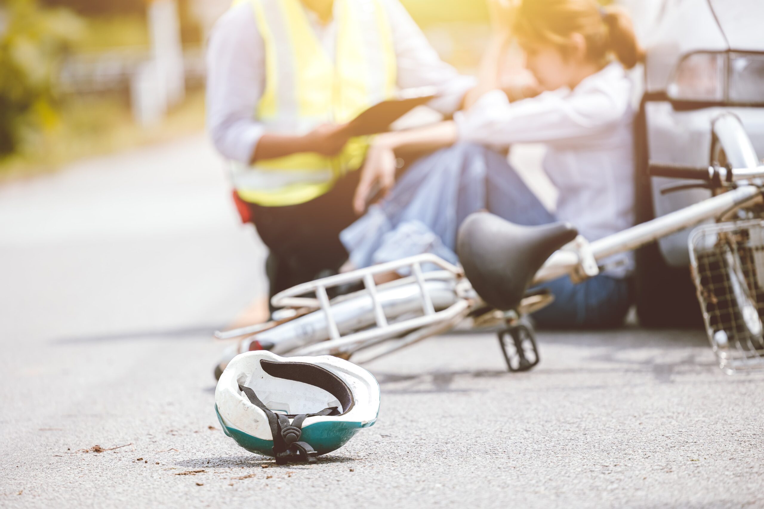 Cyclist sitting safely after a road accident while calling emergency services