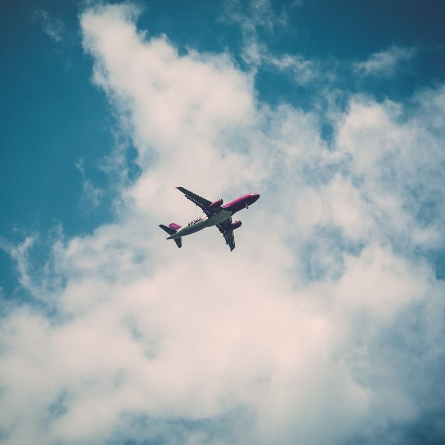 Airplane flying high in blue sky surrounded by white clouds, showcasing travel and aviation themes.