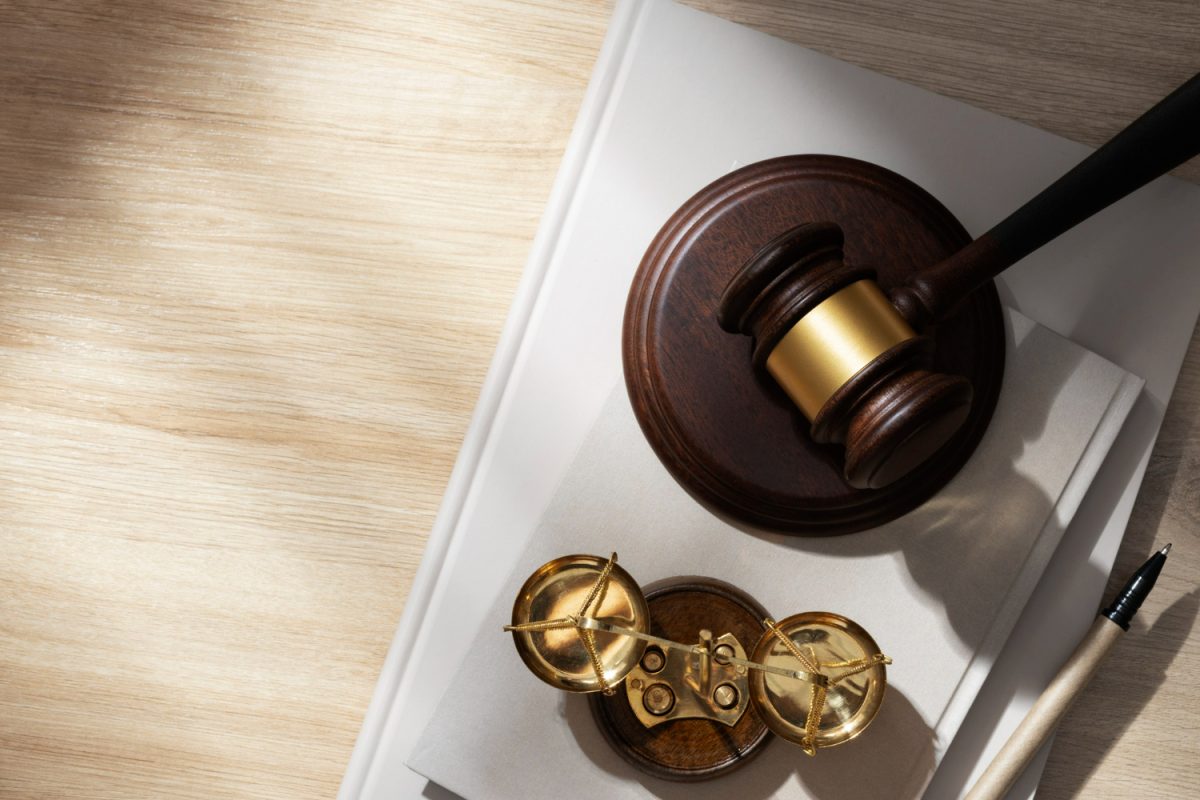 Judge's gavel and scales on legal papers symbolize justice and law decision-making on wooden desk.
