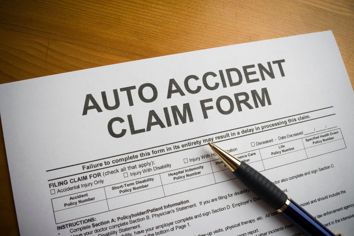 Auto accident claim form on a desk with a pen, ready for completion.