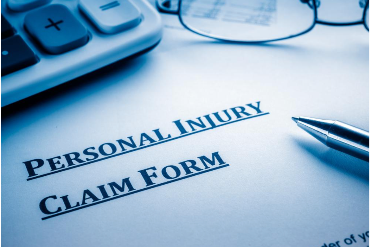Personal injury claim form with a pen, glasses, and calculator in a blue-toned setting.