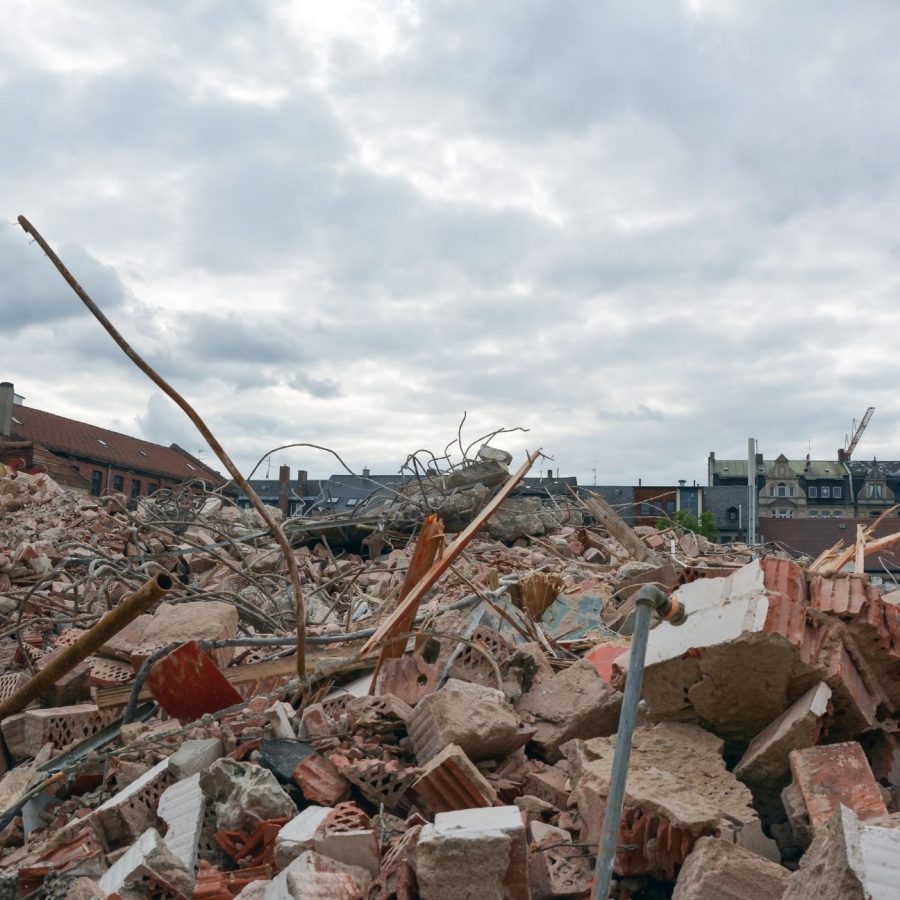 Urban demolition site with broken bricks and debris under a cloudy sky.
