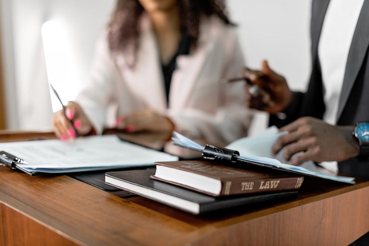 Lawyers reviewing documents at a desk with law book and paperwork, focused on legal analysis and consultation.