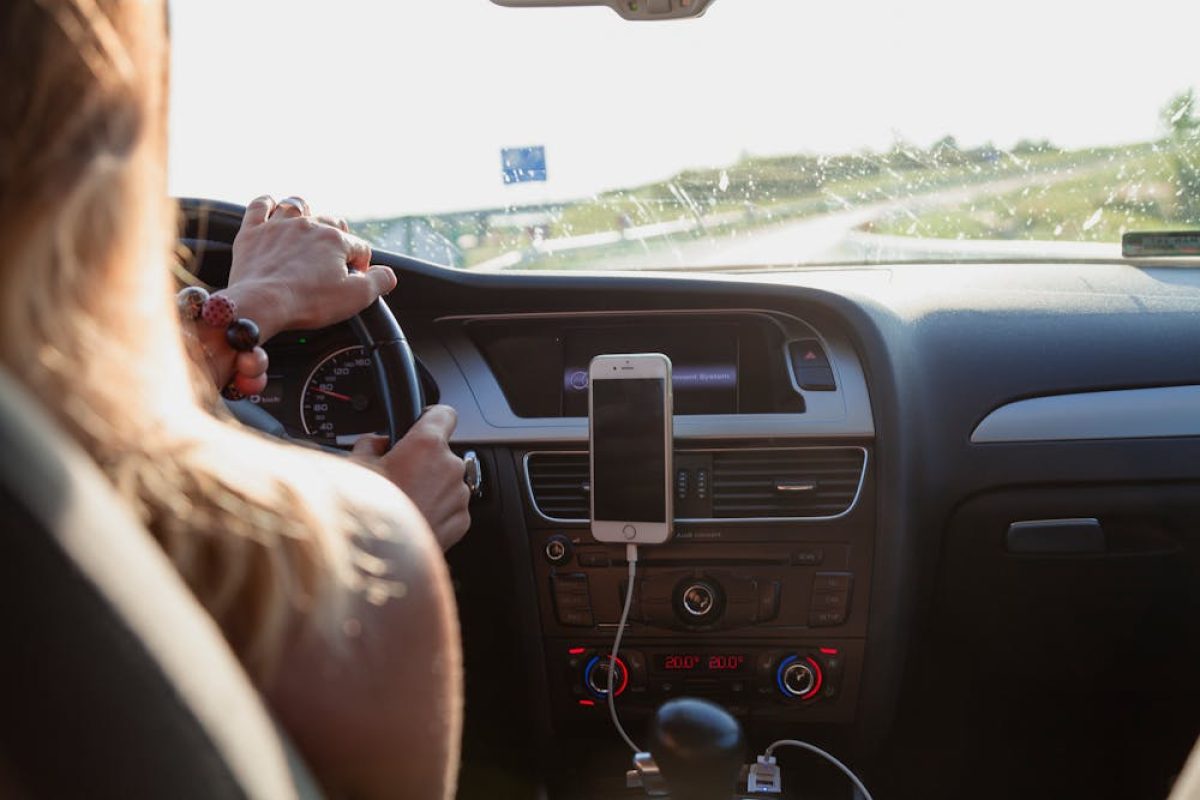 Driver on highway using phone navigation in car dashboard phone holder.