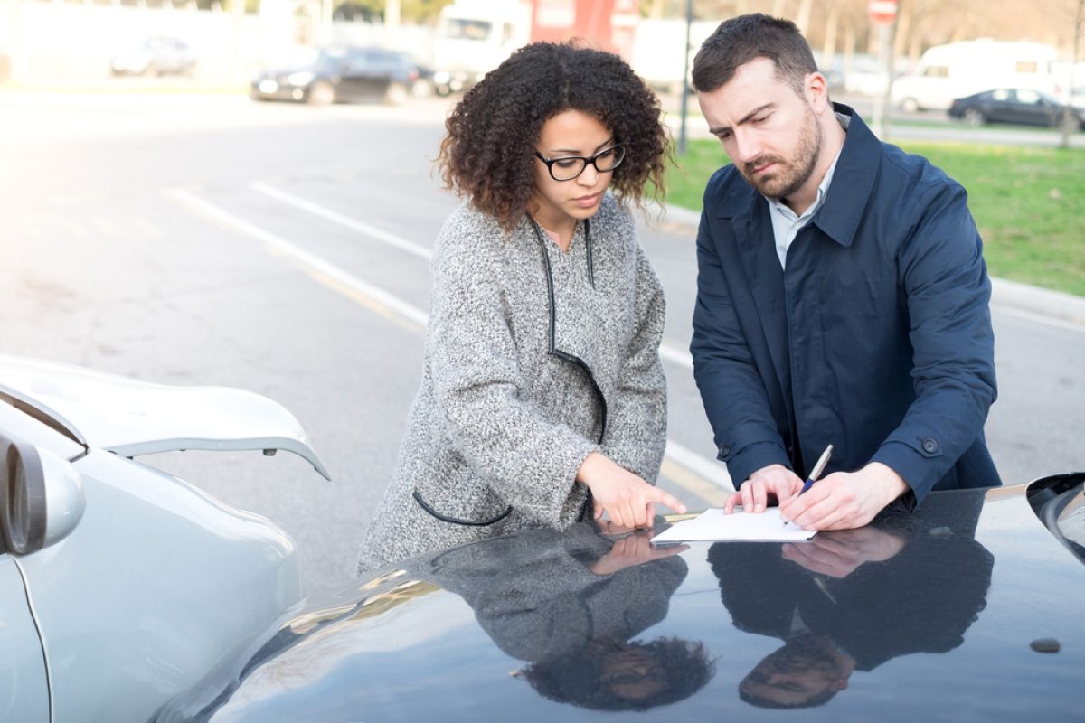 Two people exchanging information after a minor car accident on a city street.